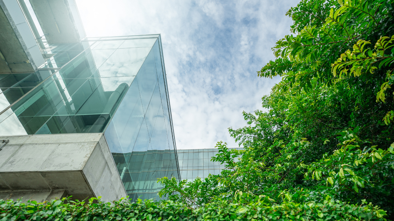 An image of a glass building, sky and greenery